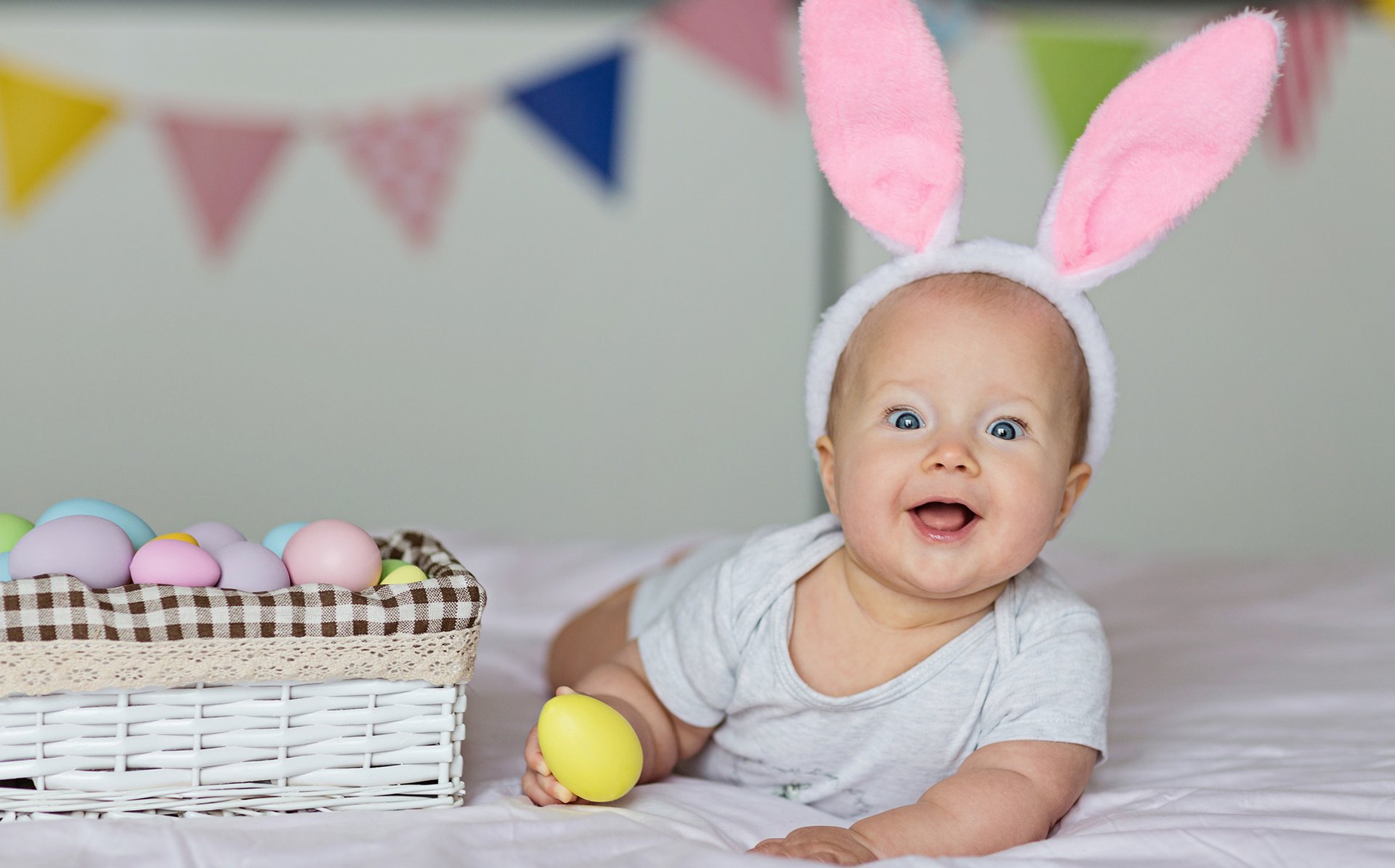 Male dziecko z opaska z uszami krolika trzyma w raczce jajko